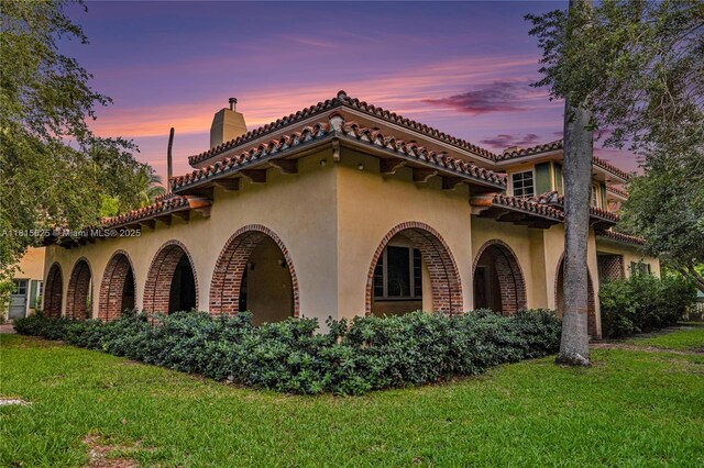 5905 N Bay Rd, Miami Beach, FL 33140 - view of front of property with stucco siding, a front lawn, and a chimney