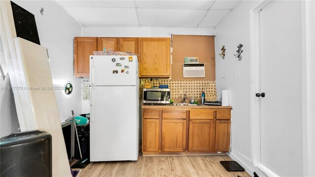 3145 Hollywood Blvd, Hollywood, FL 33021 - kitchen with freestanding refrigerator, stainless steel microwave, a drop ceiling, brown cabinetry, and light wood-type flooring