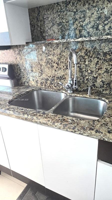 18051 Biscayne Blvd Unit 1501, Aventura, FL 33160 - kitchen view of a sink, backsplash, and white cabinetry