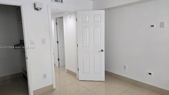 18051 Biscayne Blvd Unit 1501, Aventura, FL 33160 - unfurnished bedroom featuring a walk in closet, baseboards, light tile patterned flooring, and a closet