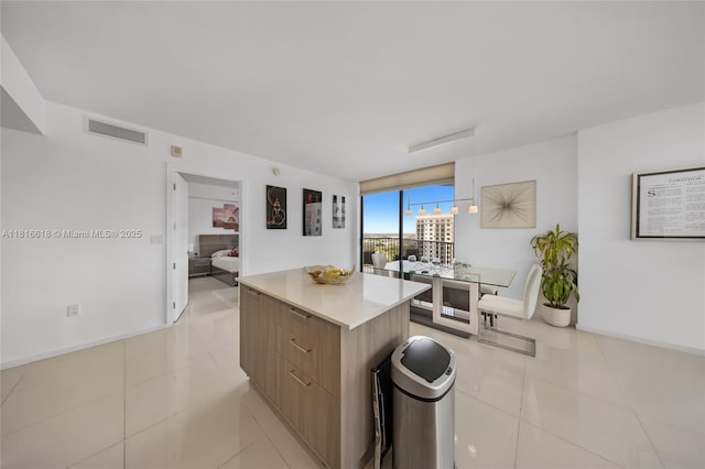 5252 NW 85th Ave Unit 1701, Doral, FL 33166 - kitchen with modern cabinets, a kitchen island, light tile patterned floors, light countertops, and baseboards