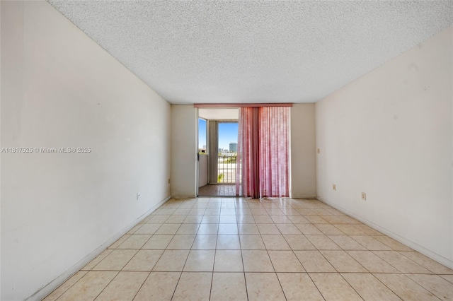 7921 Byron Ave Unit 407, Miami Beach, FL 33141 - empty room featuring a wall of windows, a textured ceiling, light tile patterned floors, and baseboards