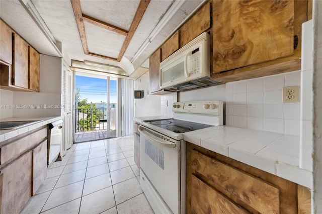 7921 Byron Ave Unit 407, Miami Beach, FL 33141 - kitchen with white appliances, tile countertops, tasteful backsplash, and brown cabinetry