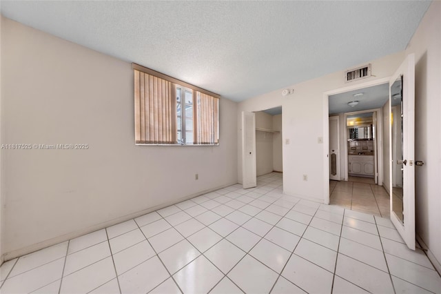 7921 Byron Ave Unit 407, Miami Beach, FL 33141 - unfurnished bedroom featuring a textured ceiling, light tile patterned floors, a closet, and baseboards