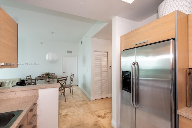2525 SW 3rd Ave Unit 711, Miami, FL 33129 - kitchen featuring stainless steel refrigerator with ice dispenser, light stone counters, hanging light fixtures, baseboards, and a sink