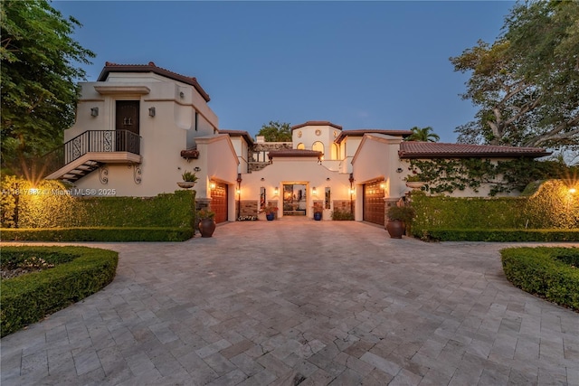 9801 SW 60th Ct, Pinecrest, FL 33156 - mediterranean / spanish-style house with decorative driveway, stucco siding, a garage, and a balcony