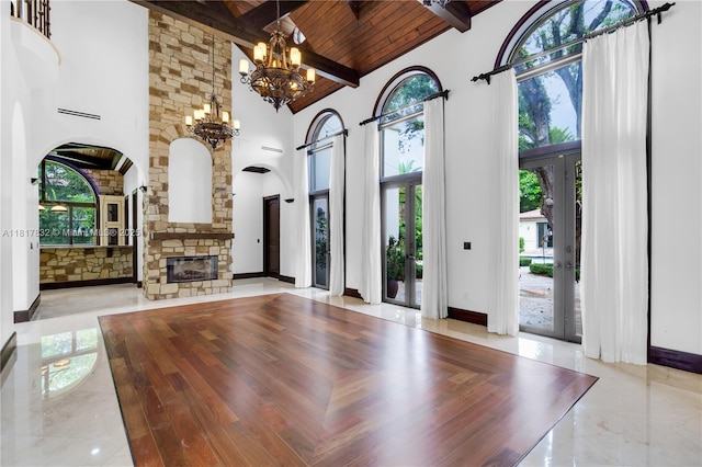 9801 SW 60th Ct, Pinecrest, FL 33156 - unfurnished living room with high vaulted ceiling, arched walkways, a chandelier, wooden ceiling with exposed beams, and a stone fireplace