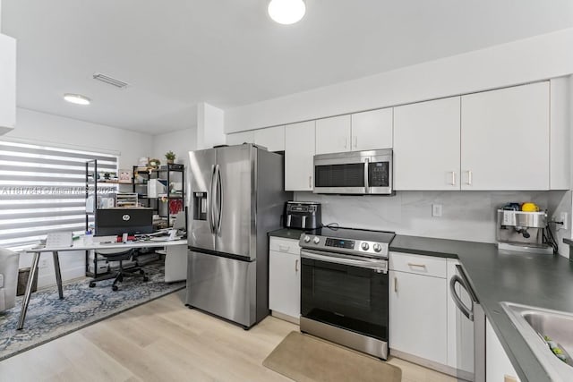 11045 SW 16th Mnr, Davie, FL 33324 - kitchen featuring stainless steel appliances, dark countertops, white cabinets, an office area, and light wood-style flooring