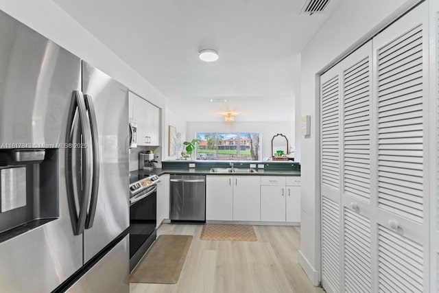 11045 SW 16th Mnr, Davie, FL 33324 - kitchen with appliances with stainless steel finishes, a sink, light wood-style floors, dark countertops, and white cabinets