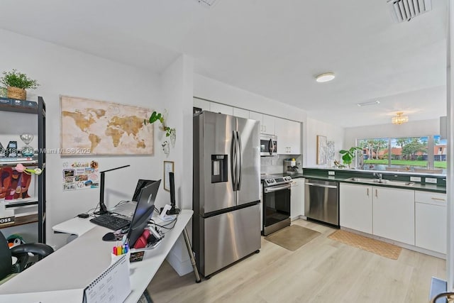 11045 SW 16th Mnr, Davie, FL 33324 - kitchen featuring stainless steel appliances, light wood finished floors, white cabinets, and a sink