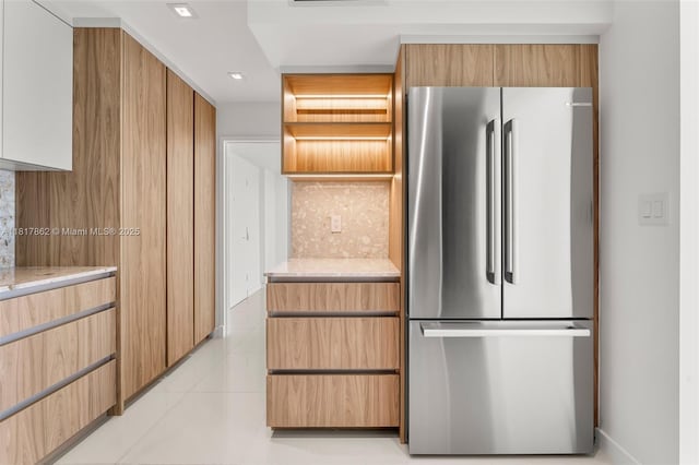 900 Bay Dr Unit 904, Miami Beach, FL 33141 - kitchen with freestanding refrigerator, light tile patterned floors, light stone counters, and backsplash