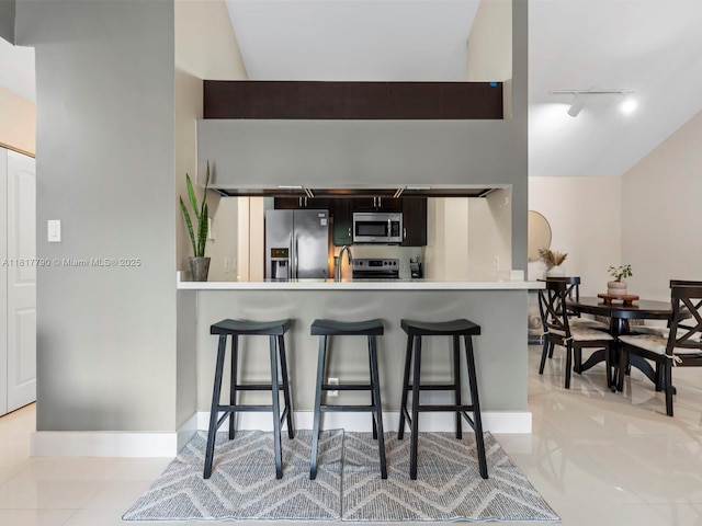 10421 SW 157th Pl Unit 301, Miami, FL 33196 - kitchen with stainless steel appliances, rail lighting, a kitchen breakfast bar, light countertops, and light tile patterned floors