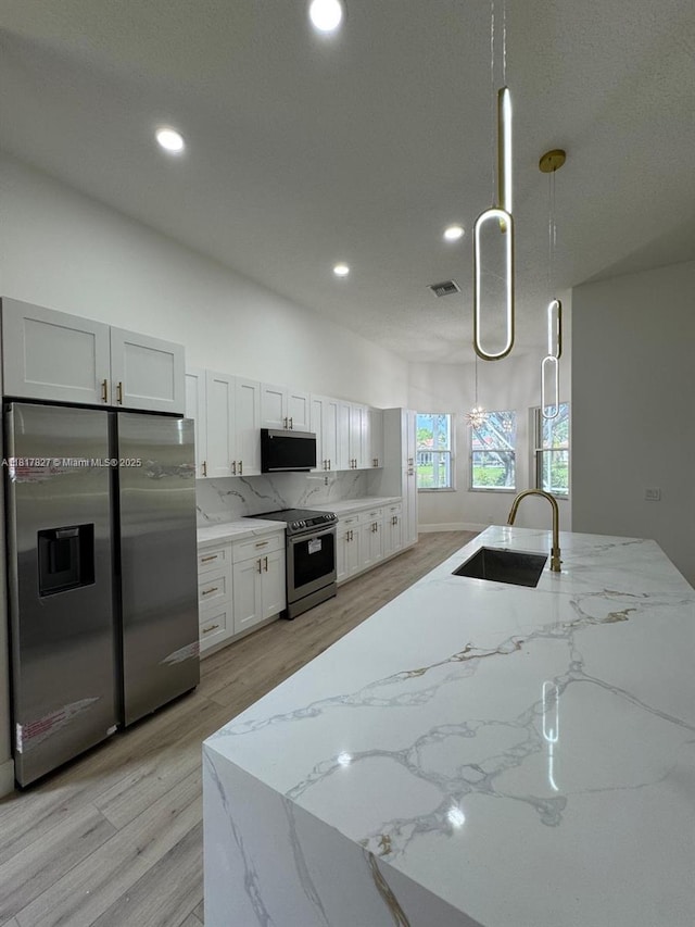 7020 Demedici Cir, Delray Beach, FL 33446 - kitchen featuring appliances with stainless steel finishes, tasteful backsplash, light stone counters, light wood-style flooring, and recessed lighting