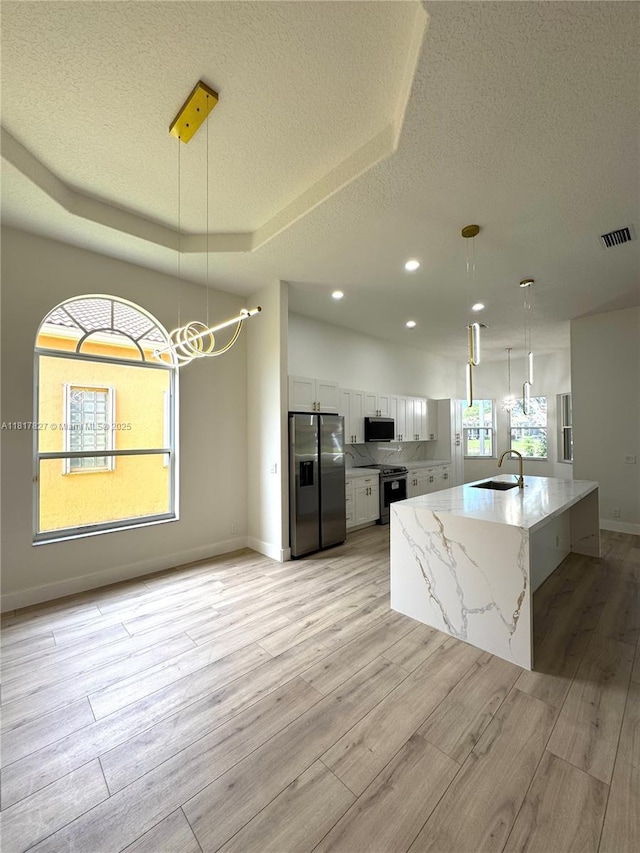 7020 Demedici Cir, Delray Beach, FL 33446 - kitchen with stainless steel appliances, a textured ceiling, white cabinets, a chandelier, and light wood-style flooring