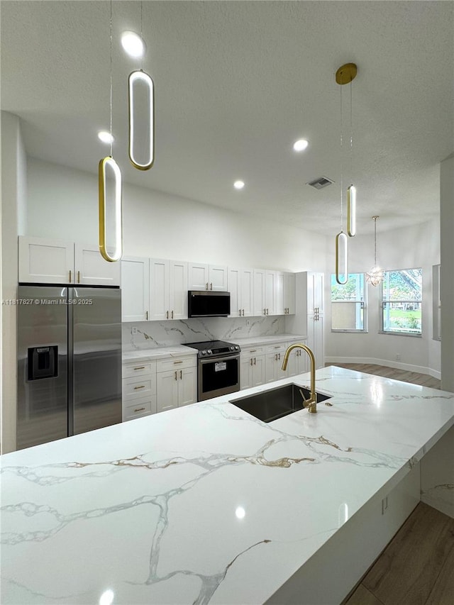 7020 Demedici Cir, Delray Beach, FL 33446 - kitchen featuring appliances with stainless steel finishes, light stone countertops, white cabinetry, wood finished floors, and recessed lighting