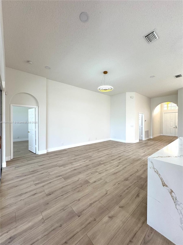 7020 Demedici Cir, Delray Beach, FL 33446 - unfurnished living room with arched walkways, light wood-style flooring, and a textured ceiling