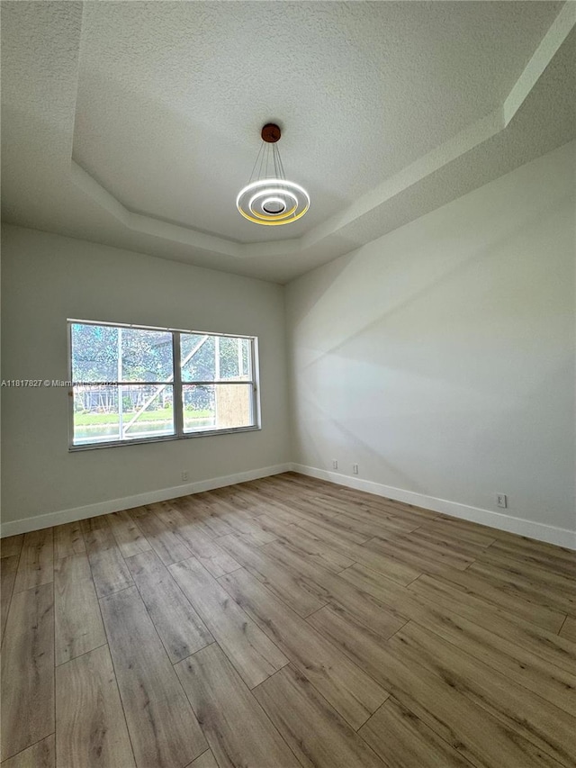 7020 Demedici Cir, Delray Beach, FL 33446 - empty room featuring a raised ceiling, a textured ceiling, a chandelier, and wood finished floors