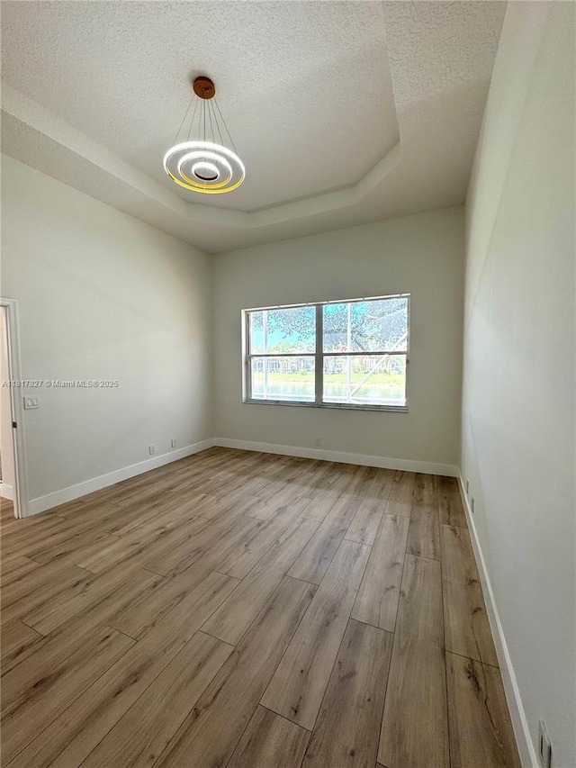 7020 Demedici Cir, Delray Beach, FL 33446 - unfurnished room featuring a tray ceiling, wood finished floors, a textured ceiling, and a chandelier