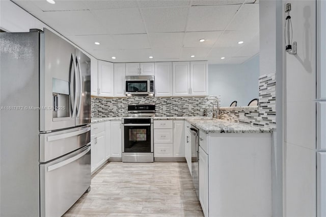 1449 NW 122nd Ter, Pembroke Pines, FL 33026 - kitchen with appliances with stainless steel finishes, white cabinetry, a drop ceiling, light stone counters, and light wood finished floors
