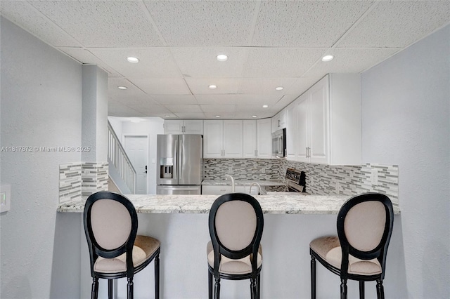 1449 NW 122nd Ter, Pembroke Pines, FL 33026 - kitchen featuring appliances with stainless steel finishes, a peninsula, decorative backsplash, a paneled ceiling, and recessed lighting