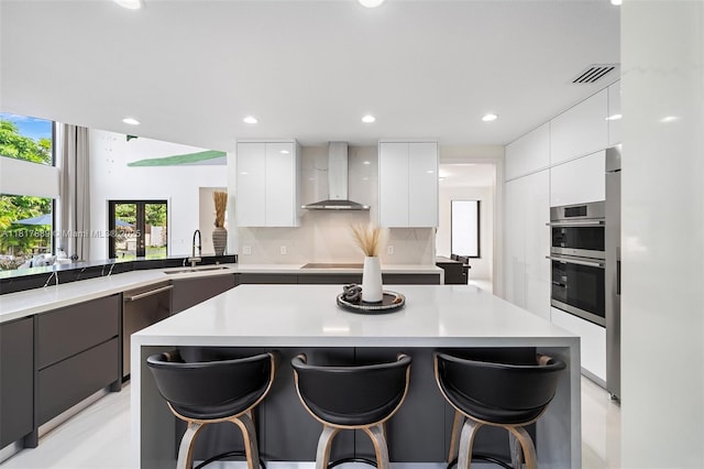 3461 SW 145th Ave, Miramar, FL 33027 - kitchen featuring modern cabinets, wall chimney exhaust hood, a sink, a kitchen bar, and recessed lighting