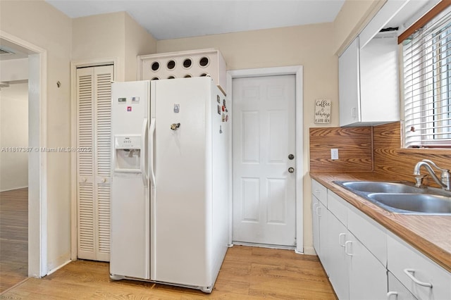 3241 SW 20th St, Miami, FL 33145 - kitchen featuring white refrigerator with ice dispenser, a sink, light wood-style flooring, and white cabinets