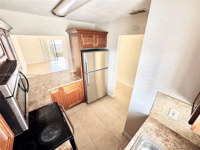 6121 W 24th Ave Unit 204, Hialeah, FL 33016 - kitchen featuring freestanding refrigerator, light countertops, light tile patterned floors, and brown cabinets