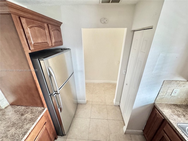 6121 W 24th Ave Unit 204, Hialeah, FL 33016 - kitchen featuring freestanding refrigerator, baseboards, light tile patterned floors, and brown cabinets
