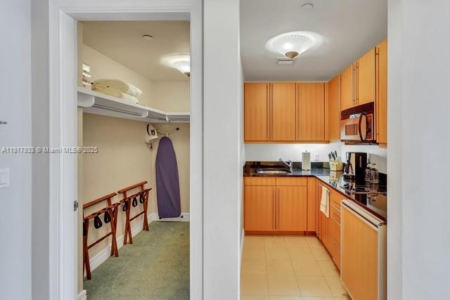 1435 Brickell Ave Unit 3011, Miami, FL 33131 - kitchen with stainless steel microwave, dark countertops, dishwashing machine, a sink, and baseboards