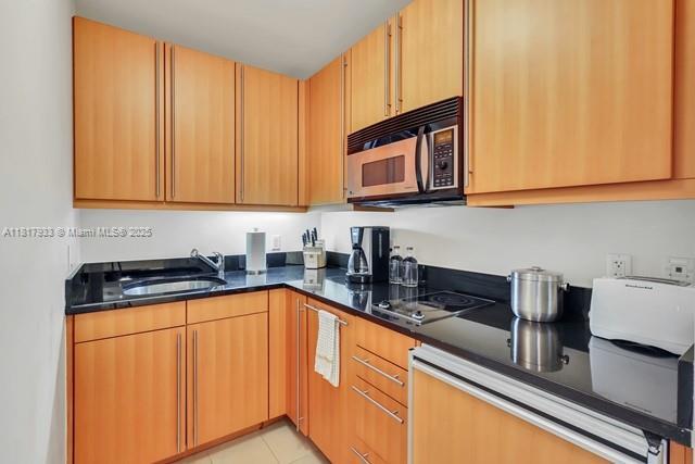 1435 Brickell Ave Unit 3011, Miami, FL 33131 - kitchen featuring black appliances, a sink, light tile patterned flooring, and dark stone counters