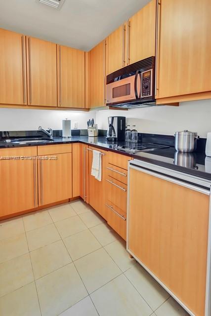 1435 Brickell Ave Unit 3011, Miami, FL 33131 - kitchen featuring dark countertops, light tile patterned floors, and electric cooktop