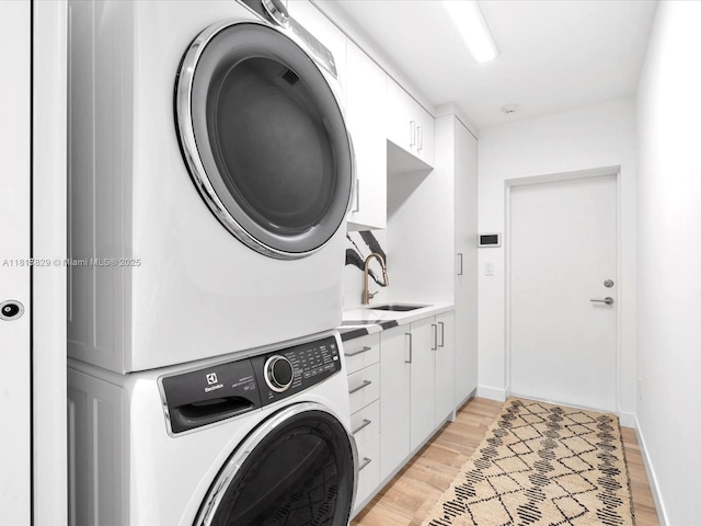 2371 Bayview Ln, North Miami, FL 33181 - laundry room with estacked washer and dryer, cabinet space, light wood finished floors, and baseboards