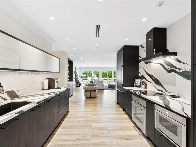2371 Bayview Ln, North Miami, FL 33181 - kitchen featuring stainless steel oven, modern cabinets, light wood-type flooring, wall chimney range hood, and recessed lighting