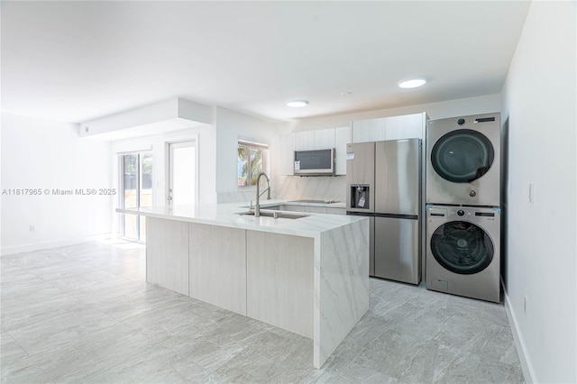 13900 SW 65th Ter Unit 9, Miami, FL 33183 - kitchen featuring stainless steel appliances, stacked washer / dryer, a sink, light stone counters, and baseboards