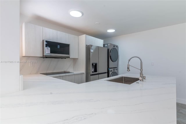 13900 SW 65th Ter Unit 9, Miami, FL 33183 - kitchen featuring stainless steel refrigerator with ice dispenser, stacked washer / dryer, light stone countertops, a sink, and black electric cooktop