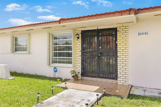 10845 SW 26th Ter, Miami, FL 33165 - entrance to property featuring brick siding, stucco siding, and a lawn