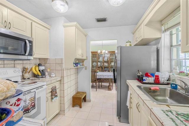 10845 SW 26th Ter, Miami, FL 33165 - kitchen with stainless steel appliances, tile counters, light tile patterned floors, a sink, and a chandelier
