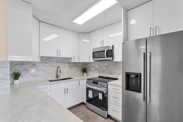 6221 NW 37th Ter, Virginia Gardens, FL 33166 - kitchen featuring appliances with stainless steel finishes, white cabinets, tasteful backsplash, and light wood finished floors