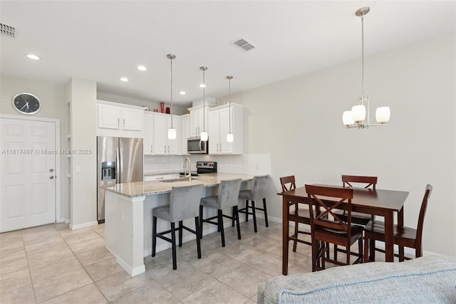 2200 Garden Belle Dr, Clermont, FL 34711 - kitchen featuring appliances with stainless steel finishes, a peninsula, a breakfast bar, decorative backsplash, and white cabinetry