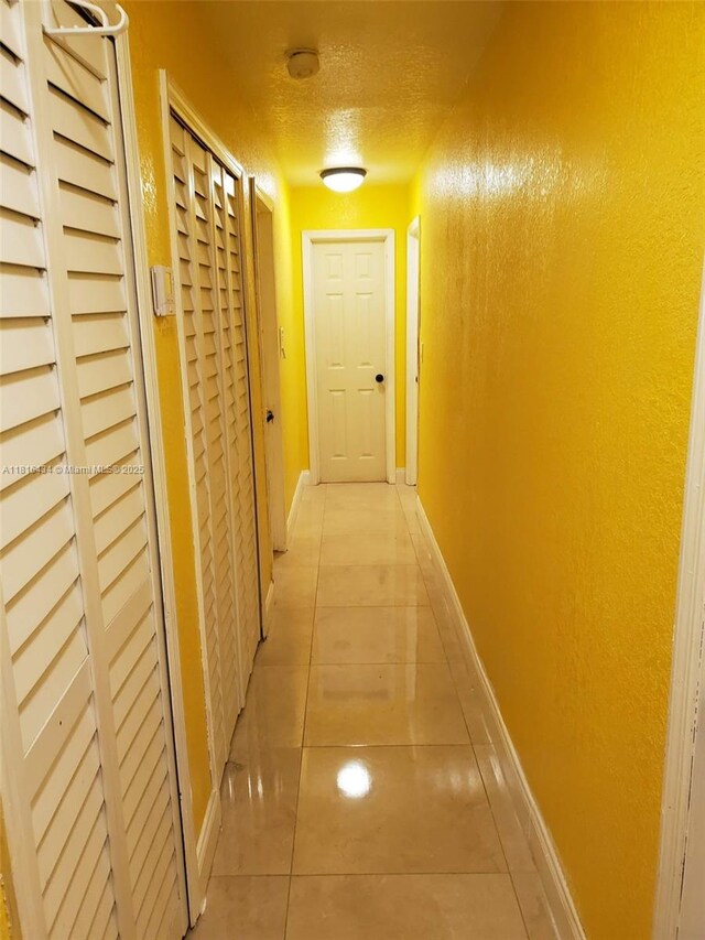 14880 SW 56th Ter, Miami, FL 33193 - hall featuring light tile patterned floors, baseboards, and a textured ceiling