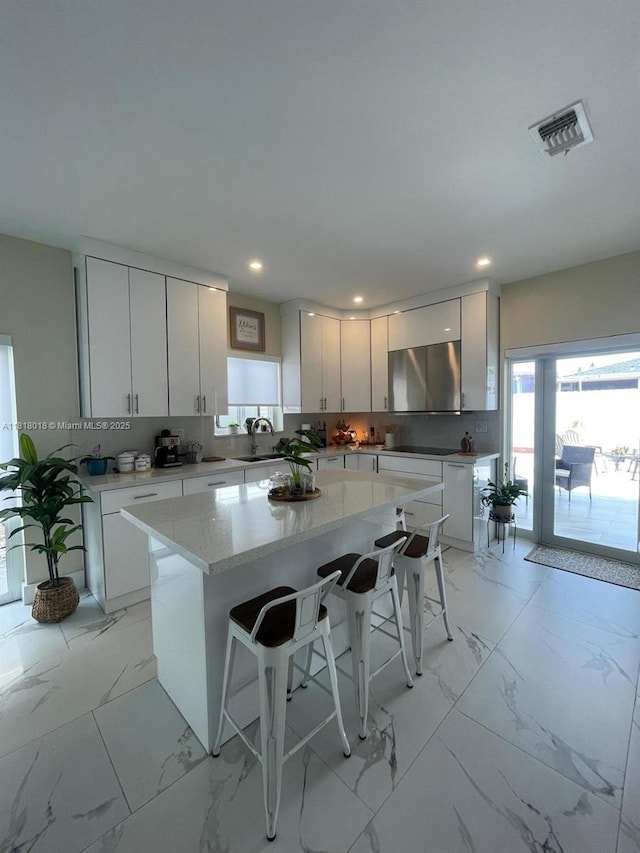 12453 SW 197th Ter, Miami, FL 33177 - kitchen featuring a sink, a kitchen bar, a center island, light marble finish flooring, and white cabinets