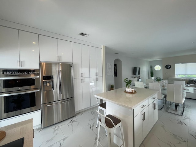 12453 SW 197th Ter, Miami, FL 33177 - kitchen featuring appliances with stainless steel finishes, light marble finish flooring, arched walkways, and white cabinetry