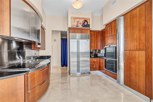 18101 Collins Ave Unit 5401, Sunny Isles Beach, FL 33160 - kitchen featuring built in fridge, brown cabinets, modern cabinets, and tasteful backsplash