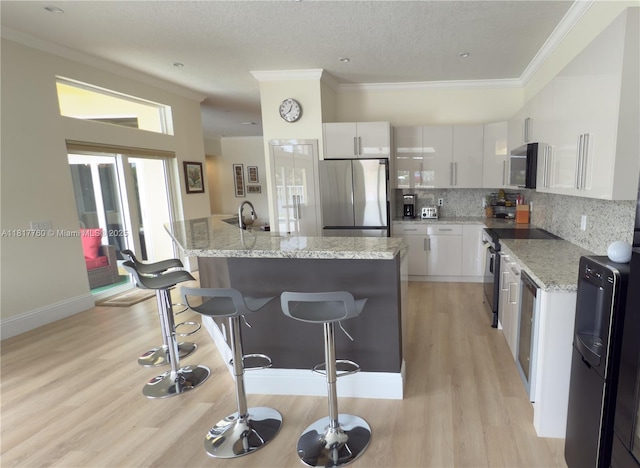 4221 Laurel Ridge Cir, Weston, FL 33331 - kitchen featuring stainless steel appliances, a kitchen bar, light wood-style flooring, white cabinets, and a center island with sink