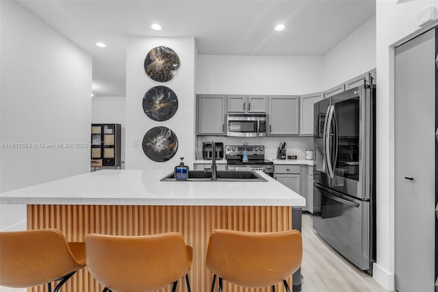 685 SE 34th Ter, Homestead, FL 33033 - kitchen with appliances with stainless steel finishes, gray cabinets, a sink, a kitchen breakfast bar, and light countertops