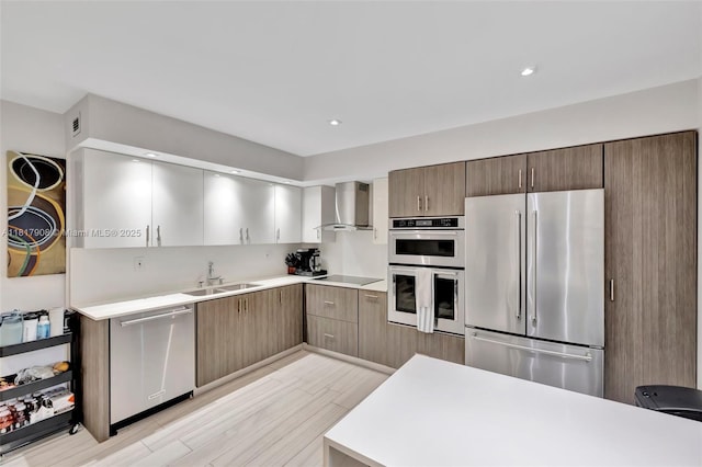 2730 NE 183rd St Unit Th03, Aventura, FL 33160 - kitchen featuring appliances with stainless steel finishes, wall chimney range hood, a sink, light countertops, and light wood-style flooring