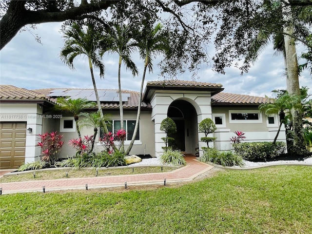13357 SW 42nd St, Davie, FL 33330 - mediterranean / spanish-style house with an attached garage, roof mounted solar panels, a tile roof, a front yard, and stucco siding