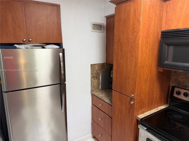 7840 SW 55th Ave Unit 23C, Miami, FL 33143 - kitchen featuring freestanding refrigerator, range with electric stovetop, black microwave, and brown cabinetry
