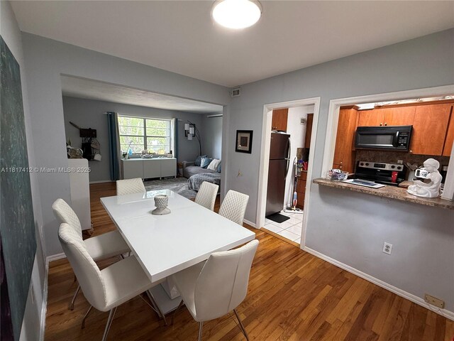 7840 SW 55th Ave Unit 23C, Miami, FL 33143 - dining room with baseboards and light wood-type flooring