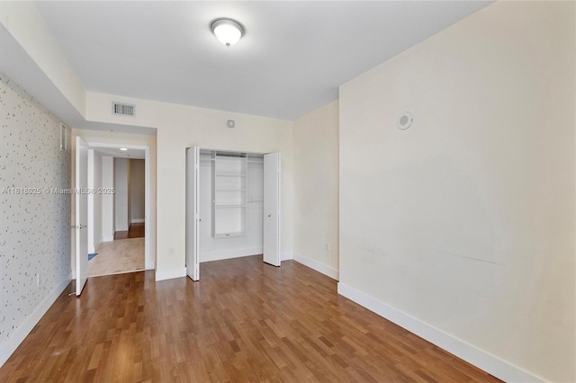 3030 NE 188th St Unit 609, Aventura, FL 33180 - unfurnished bedroom featuring wood finished floors, baseboards, a closet, and wallpapered walls
